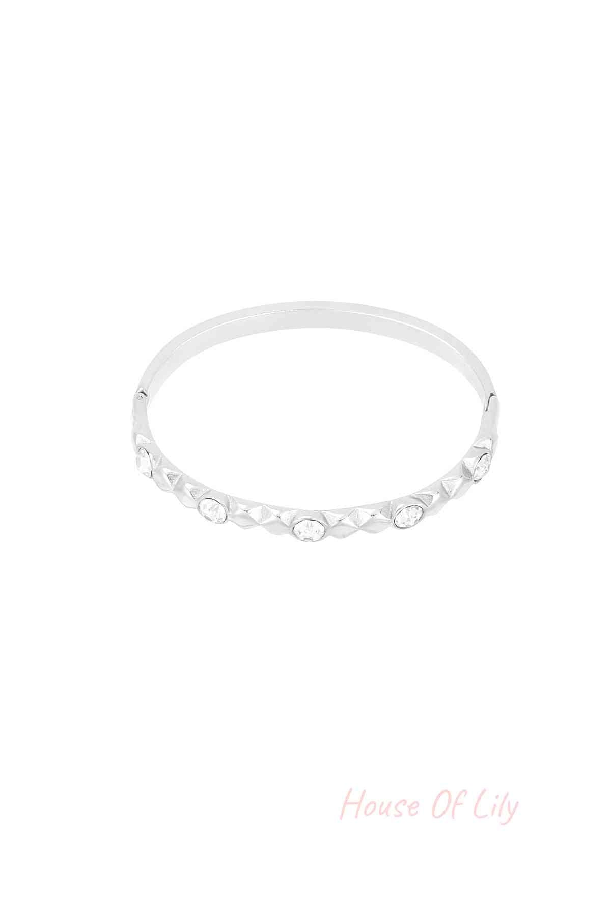 Silver tone crystal studded bangle bracelet with relief design on white background