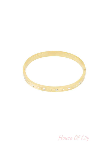 Gold-tone bangle bracelet with star-shaped engravings and crystal accents on a white background