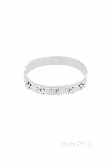 Silver floral bangle bracelet with rhinestone accents on white background