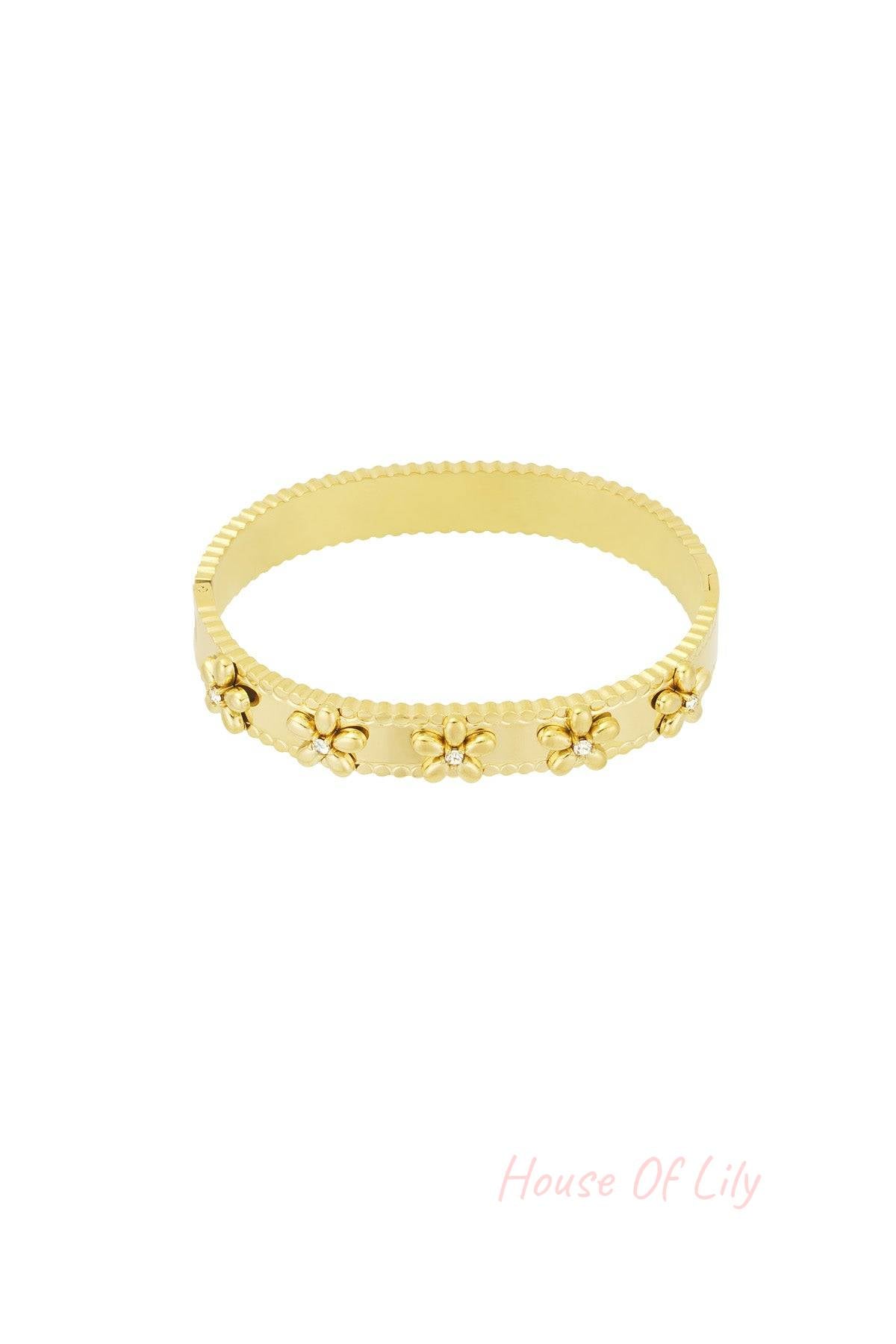 Gold floral bangle bracelet with rhinestone accents on white background