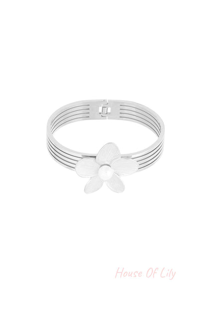 Silver-tone multi-strand bangle bracelet with textured flower and pearl centre displayed on white background