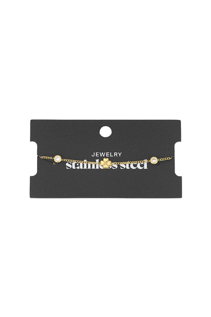 Gold four-leaf clover charm bracelet displayed on black jewellery packaging labeled stainless steel