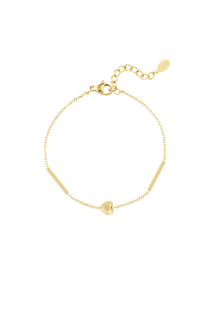 Delicate gold heart charm bracelet with fine chain and bar details laid flat on white background