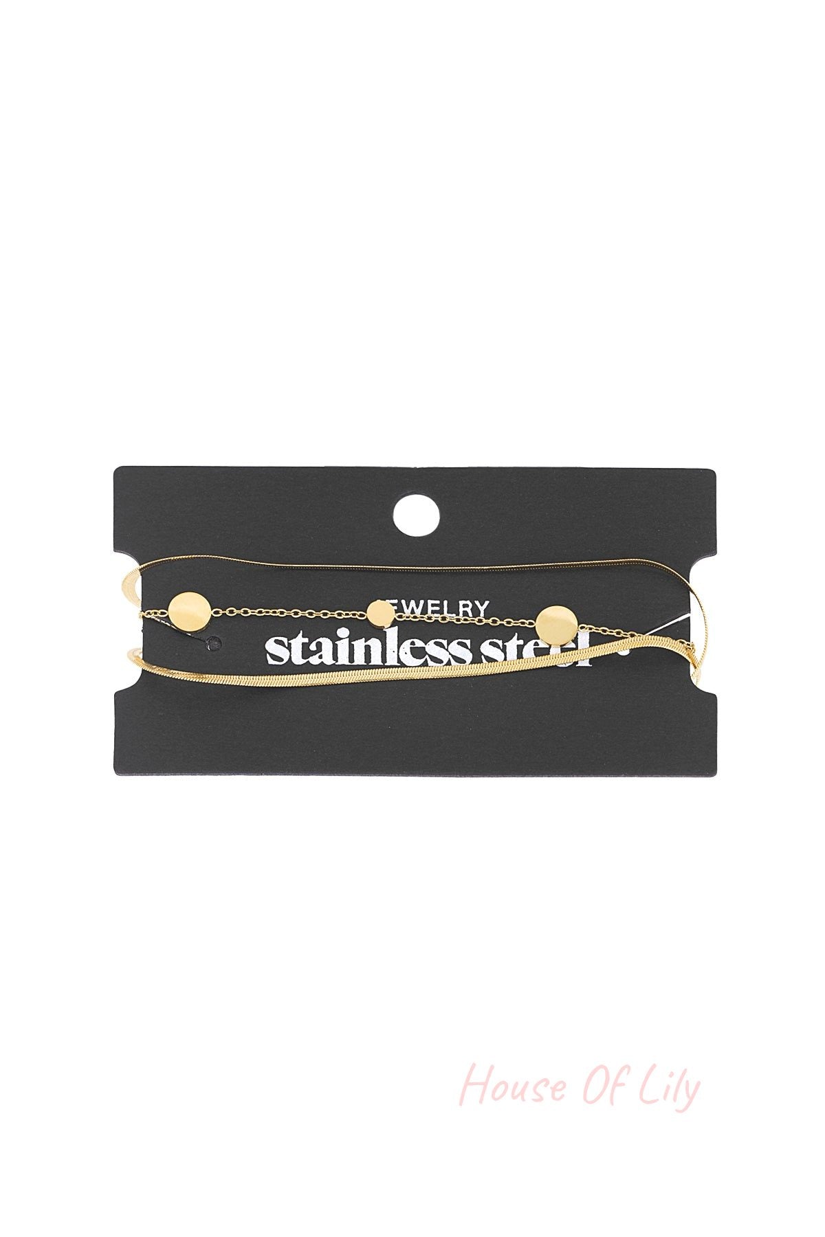 Gold-tone minimal coin charm bracelet displayed on black branded card packaging showing chain and clasp details