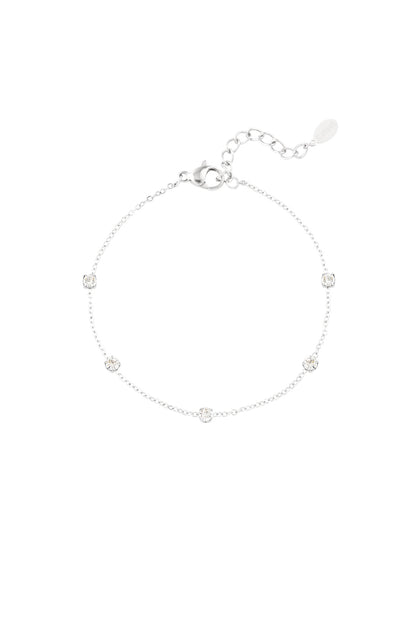 Silver delicate chain bracelet with five sparkling crystal stones evenly spaced on white background