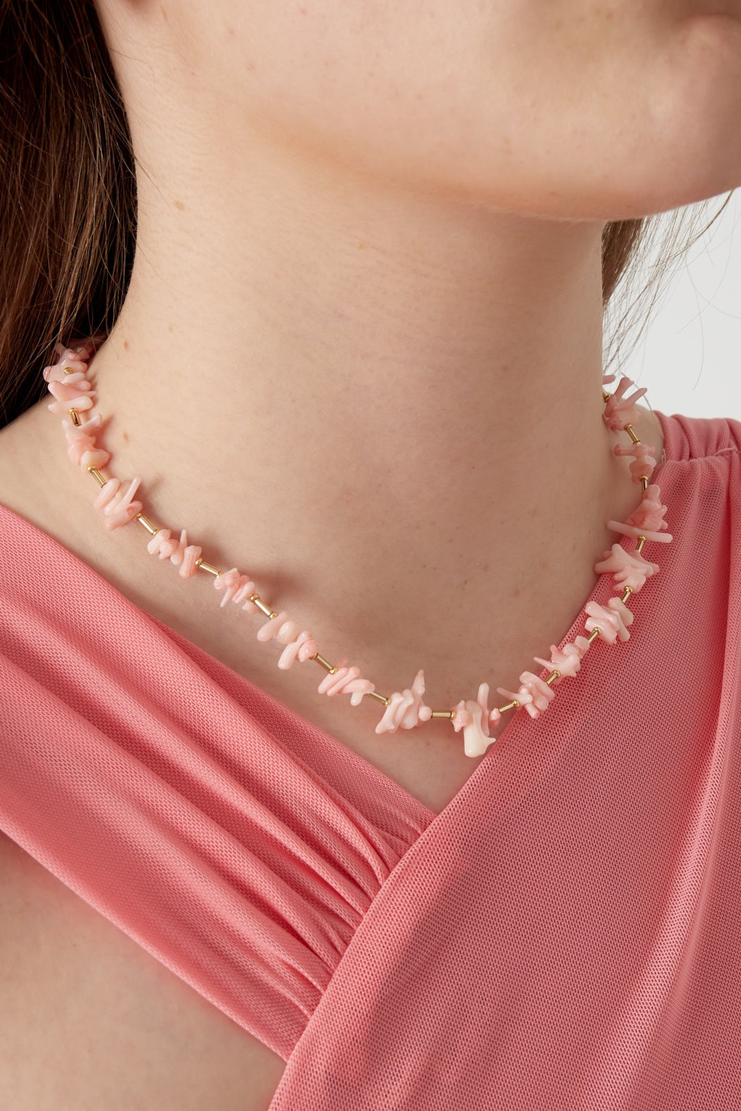 Model wearing a pastel pink coral chip necklace paired with a pink textured top