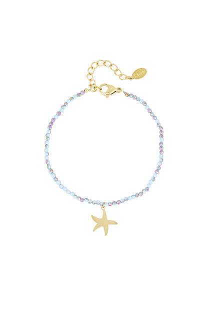 Close-up of a delicate beaded bracelet with small blue and iridescent glass beads featuring a gold starfish charm and gold adjustable clasp.