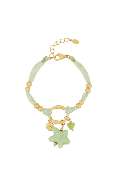 Green fabric bracelet with gold beads and hanging charms including starfish, heart, and shell on white background