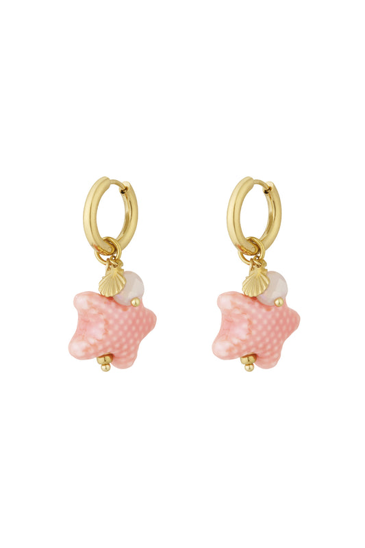 Close-up view of pink starfish charm hoop earrings with gold hoops and shell detail on white background