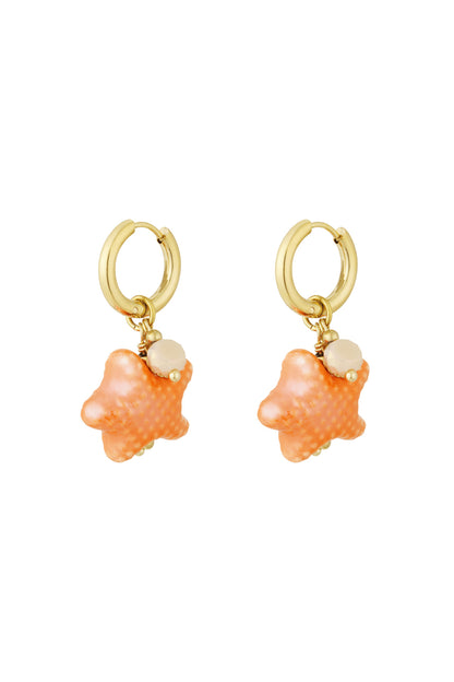 Close-up of bright orange starfish charm hoop earrings with gold-tone hoops and bead accents