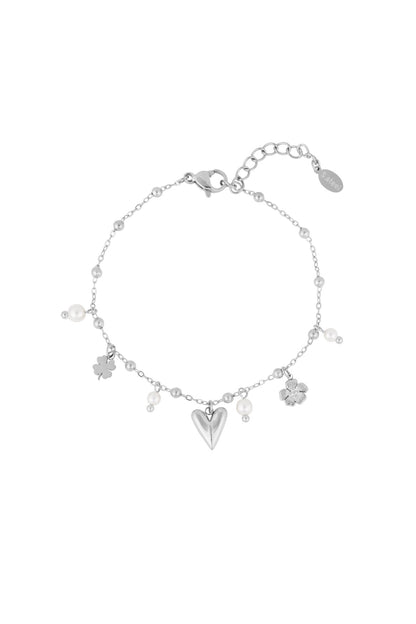 Silver-tone version of delicate charm bracelet with heart, flower, four-leaf clover charms and pearl accents on white background