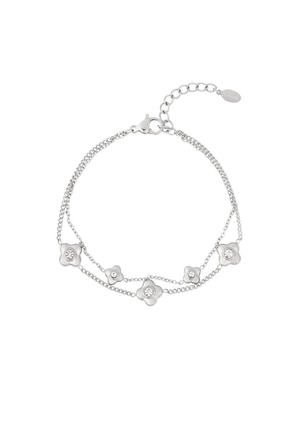 Silver double chain bracelet with flower shaped charms centered with crystals on white background