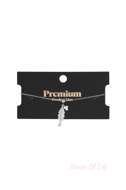 Silver tone fish pendant charm bracelet shown on a black premium product line display card