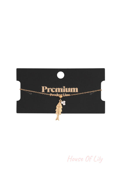 Gold tone fish pendant charm bracelet displayed on a black premium product line card