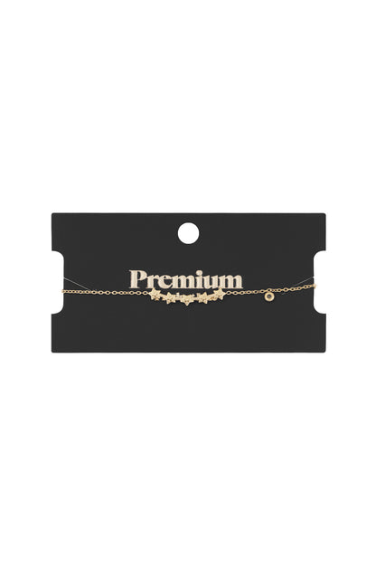 Gold star charm bracelet displayed on a black card labelled Premium showcasing its delicate chain and star charms
