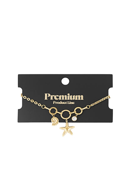Gold-tone charm bracelet displayed on black Premium Product Line card