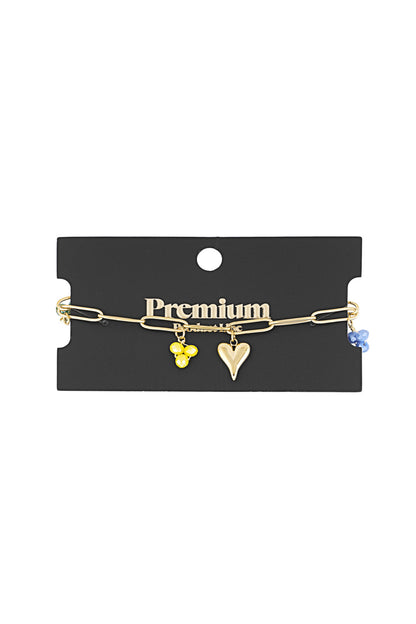 Gold charm bracelet displayed on premium black jewellery card showing yellow and blue bead charms with heart charm