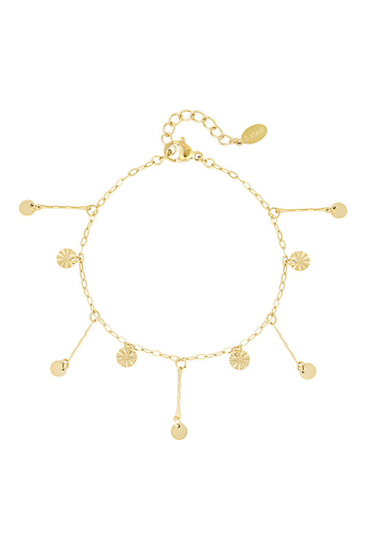 Gold coin charm bracelet laid flat showcasing delicate dangling sunburst and smooth coins on chain