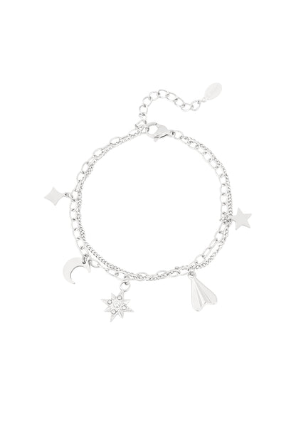 Silver-tone double chain charm bracelet with moon, star, gemstone starburst, diamond, and paper plane charms on white background
