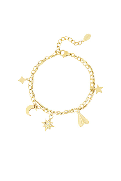 Gold-tone double chain charm bracelet with moon, star, gemstone starburst, diamond, and paper plane charms on white background