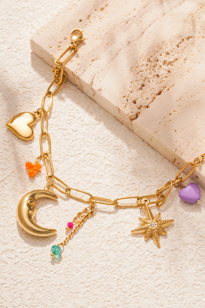 Close-up shot of bracelet on white stone highlighting crescent moon, star-shaped charm with crystal, heart charm and colourful beads