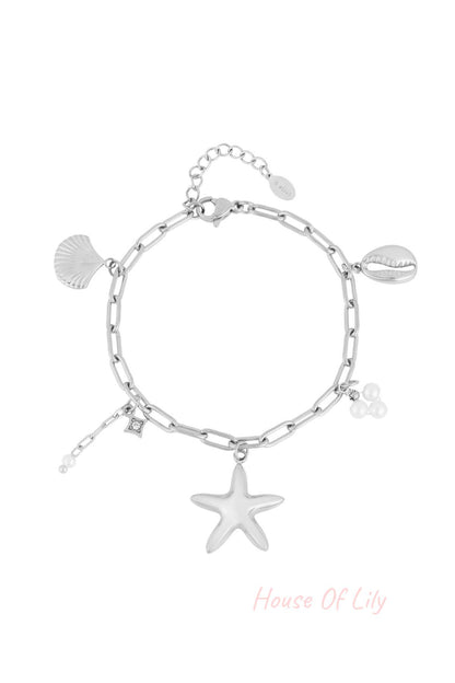 Silver-tone chain link charm bracelet with starfish, shell, cowrie shell and pearl charms laid flat on white background