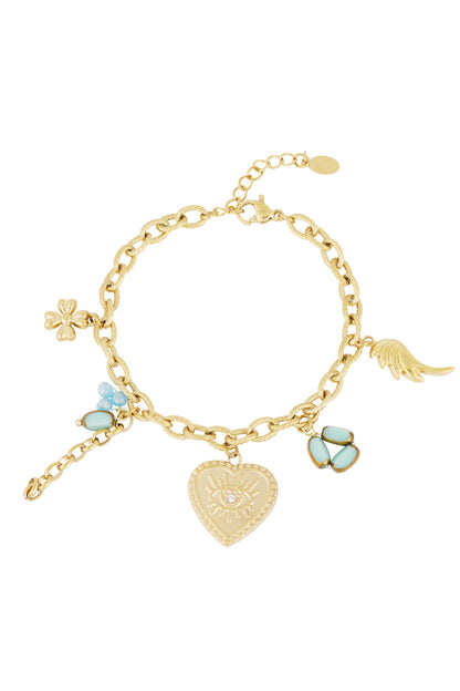 Golden charm bracelet with a heart pendant featuring an eye design, blue enamel charms, and a wing, lying flat on a white background
