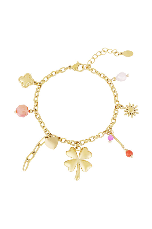Gold charm bracelet with four-leaf clover, heart, sun and colourful beads laid flat on white background