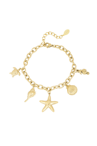Close-up of a gold chain bracelet with beach-themed charms including a starfish, turtle, seahorse, shell, and conch against white background