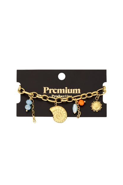 Charm bracelet displayed on black Premium Product Line card showing gold ocean-inspired charms and mixed beads