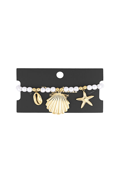 Pearl bracelet with gold-tone seaside charms displayed on black packaging card highlighting the bracelet’s design