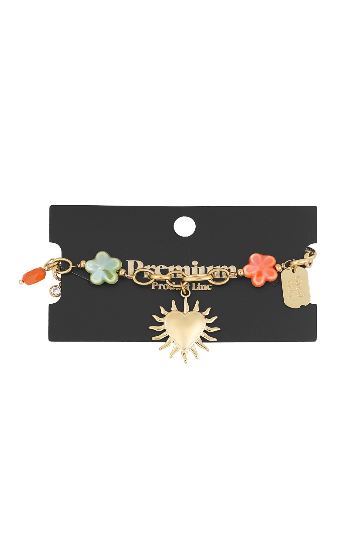 Gold-tone charm bracelet displayed on black card with branding, featuring floral beads and heart sunburst pendant with 'Good Luck' tag