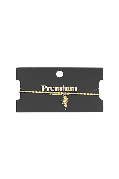 Golden beaded seashell charm bracelet displayed on a black card labeled Premium