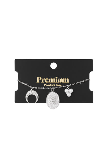 Silver-tone charm bracelet displayed on black Premium Product Line card
