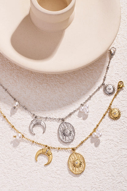 Gold and silver charm bracelets arranged on light stone backdrop near decorative ceramic piece
