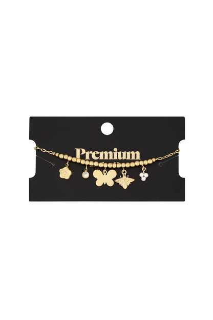 Gold-tone charm bracelet with butterfly, bee, flower, crystal, and pearl charms displayed on black Premium brand card