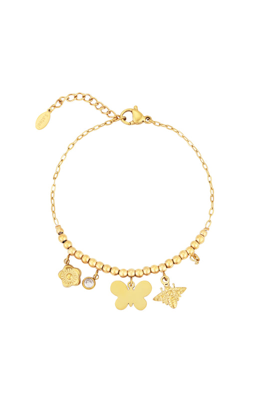 Gold-toned beaded bracelet with butterfly, bee, flower, and crystal charms displayed flat on white background