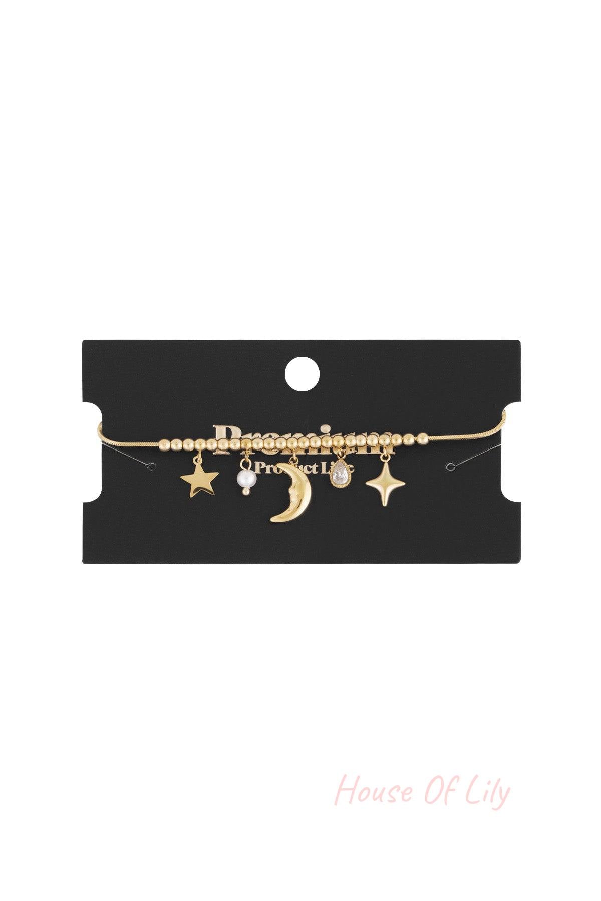 Celestial charm bracelet displayed on black branded card with moon, star, pearl, and crystal charms visible