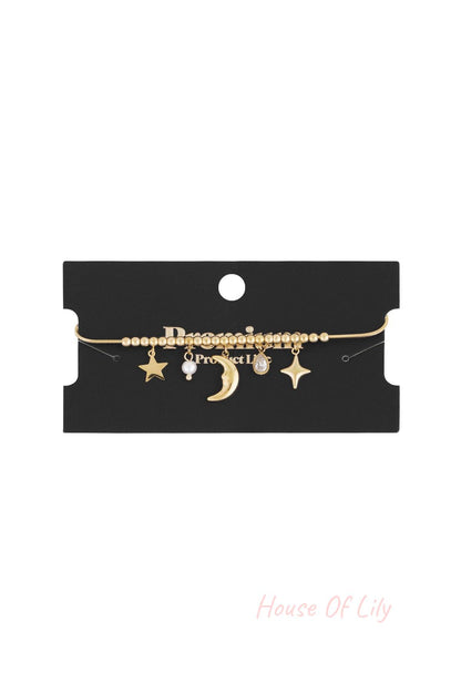 Celestial charm bracelet displayed on black branded card with moon, star, pearl, and crystal charms visible