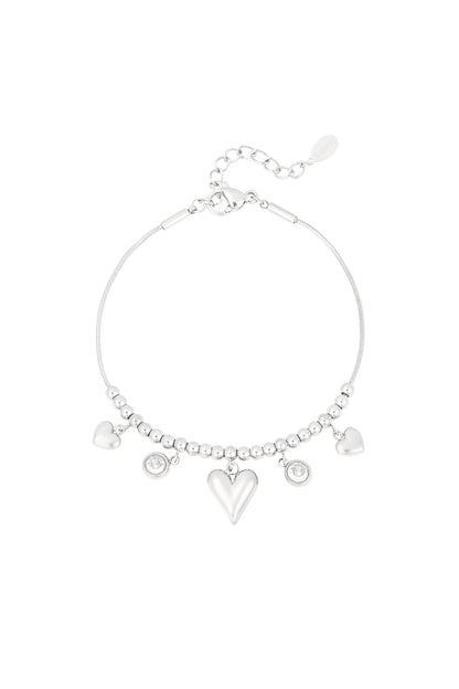 Silver heart bead bracelet with dangling heart charms and crystal accents on white background