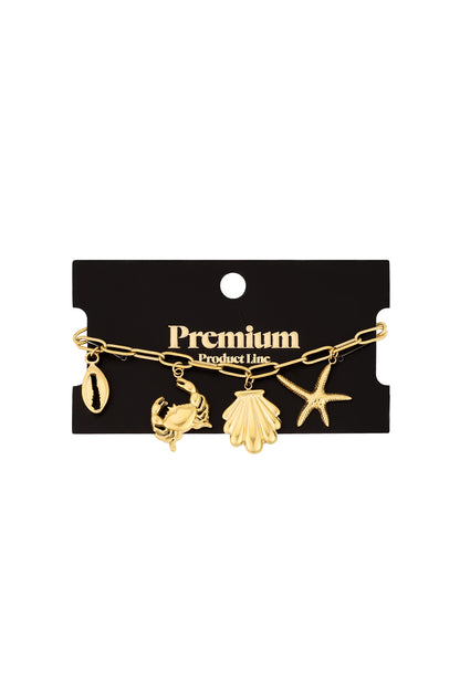 Silver-tone charm bracelet with ocean-themed charms on textured cream background