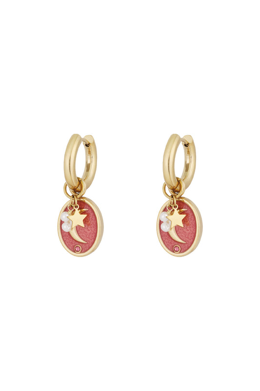 Pair of gold-tone hoop earrings with pink enamel oval charms featuring crescent moon, star, faux pearls and rhinestone details on white background