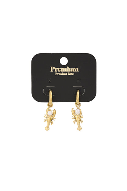 Gold lobster charm earrings on black premium product line card