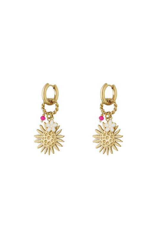 Pair of gold-tone drop earrings featuring textured sun charms, small white enamel flowers, and pink beads on hoop and twisted ring attachments.