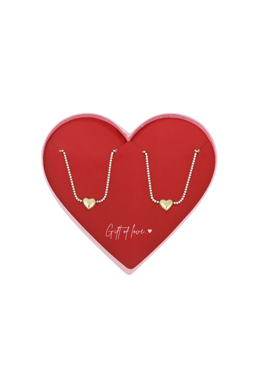 Twin heart charm bracelets with gold-tone heart pendants and sparkling crystal chain displayed on a red heart-shaped box with 'Gift of love...' text
