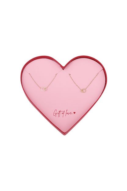 Heart-shaped pink box with two gold-tone infinity bracelets arranged inside and the message 'Gift of love' written in red