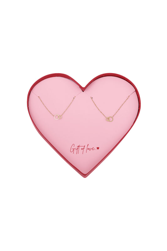 Heart-shaped pink box with two gold-tone infinity bracelets arranged inside and the message 'Gift of love' written in red