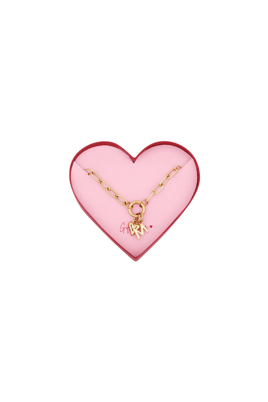 Gold-tone chain bracelet with heart and letter M charms displayed inside a pink heart-shaped gift box with red border
