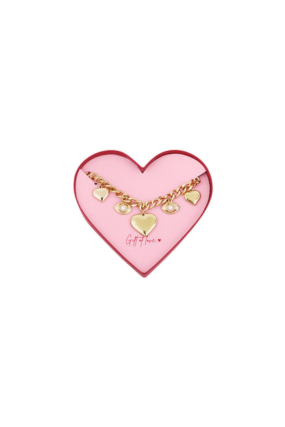 Gold-tone charm bracelet with heart and eye charms displayed inside a pink heart-shaped box