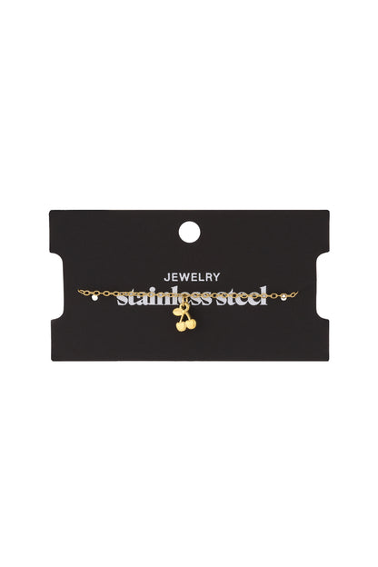 Golden cherry charm bracelet displayed on a black jewelry card labelled 'stainless steel'